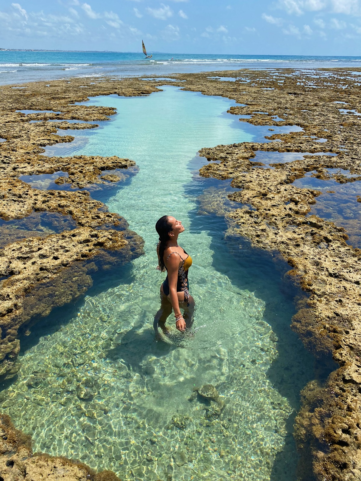 Piscina natural de águas cristalinas em Maracaípe com jangada ao fundo
