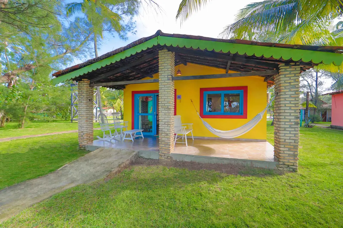 Fachada da casa ao entardecer com rede e cadeiras na varanda