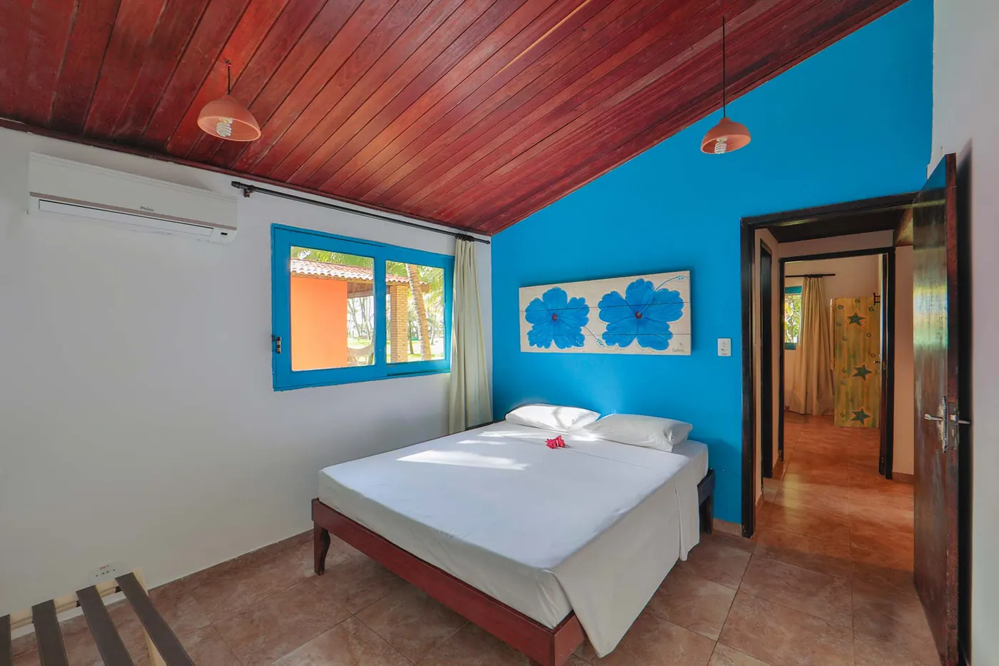 Suíte principal com cama de casal, parede azul e painel artístico