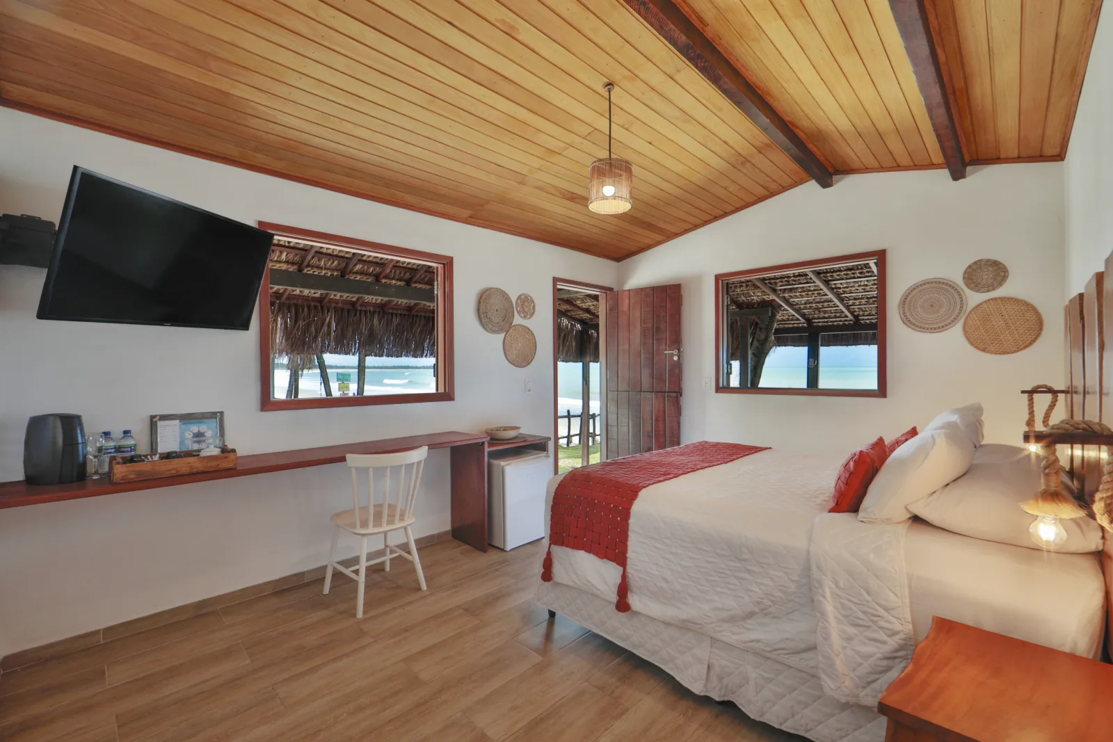 Quarto da Cabana do Mar com cama de casal, TV e janelas com vista para o mar