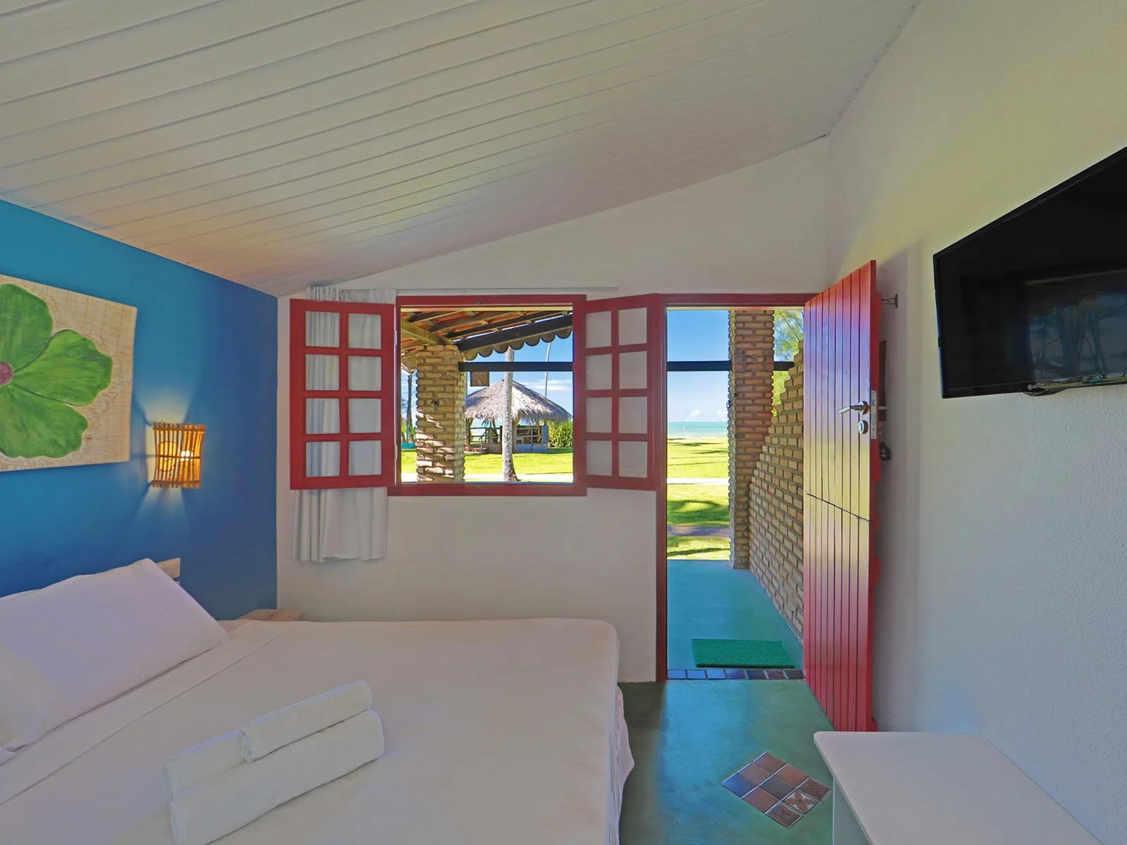 Duplo Econômico Vista Mar, quarto azul com porta vermelha aberta para o mar
