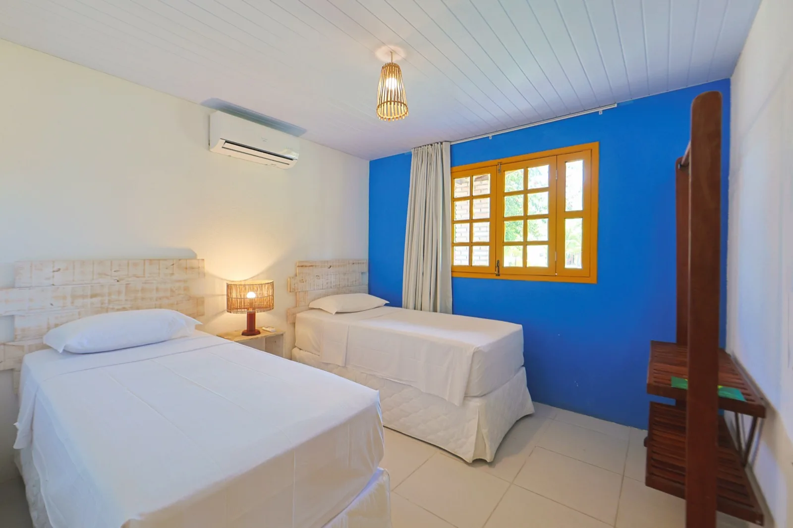 Casa Haras, segundo quarto com duas camas de solteiro e parede azul com janela amarela
