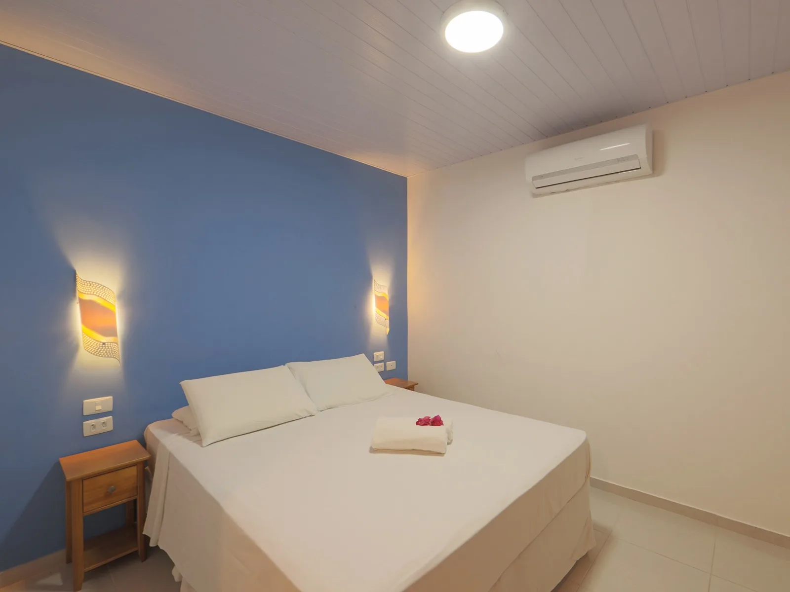 Vista Jardim, quarto de casal com parede azul e ar-condicionado split