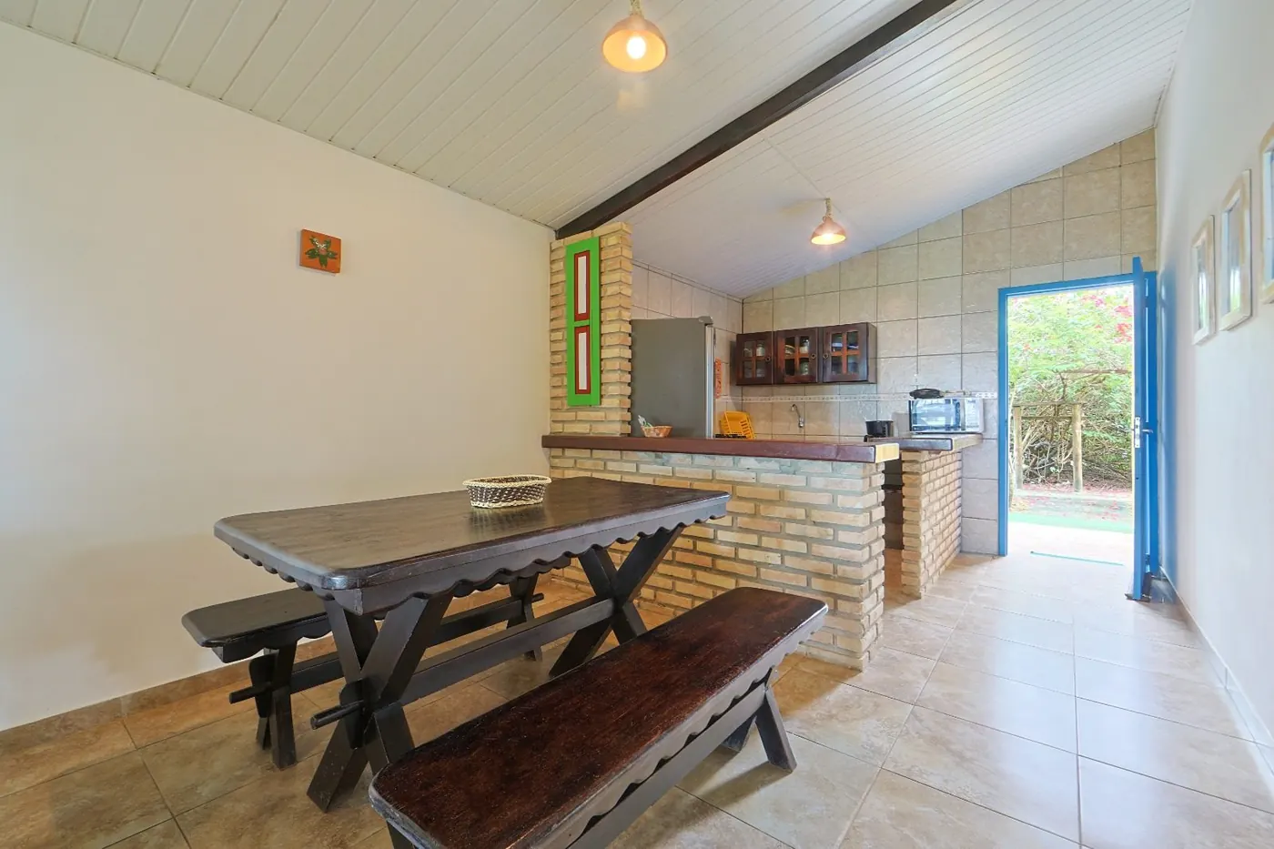 Sala de jantar com mesa rústica de madeira e acesso à cozinha