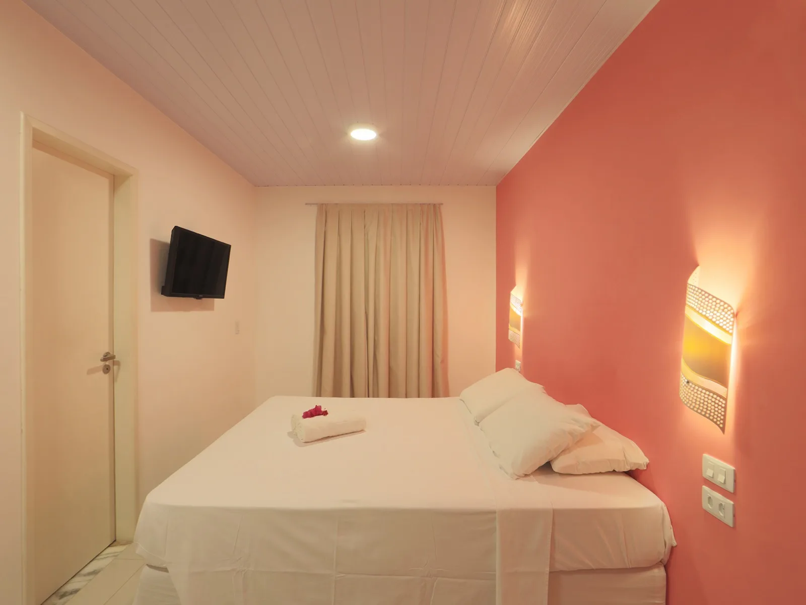Vista Jardim, quarto de casal com parede coral e luminárias artesanais