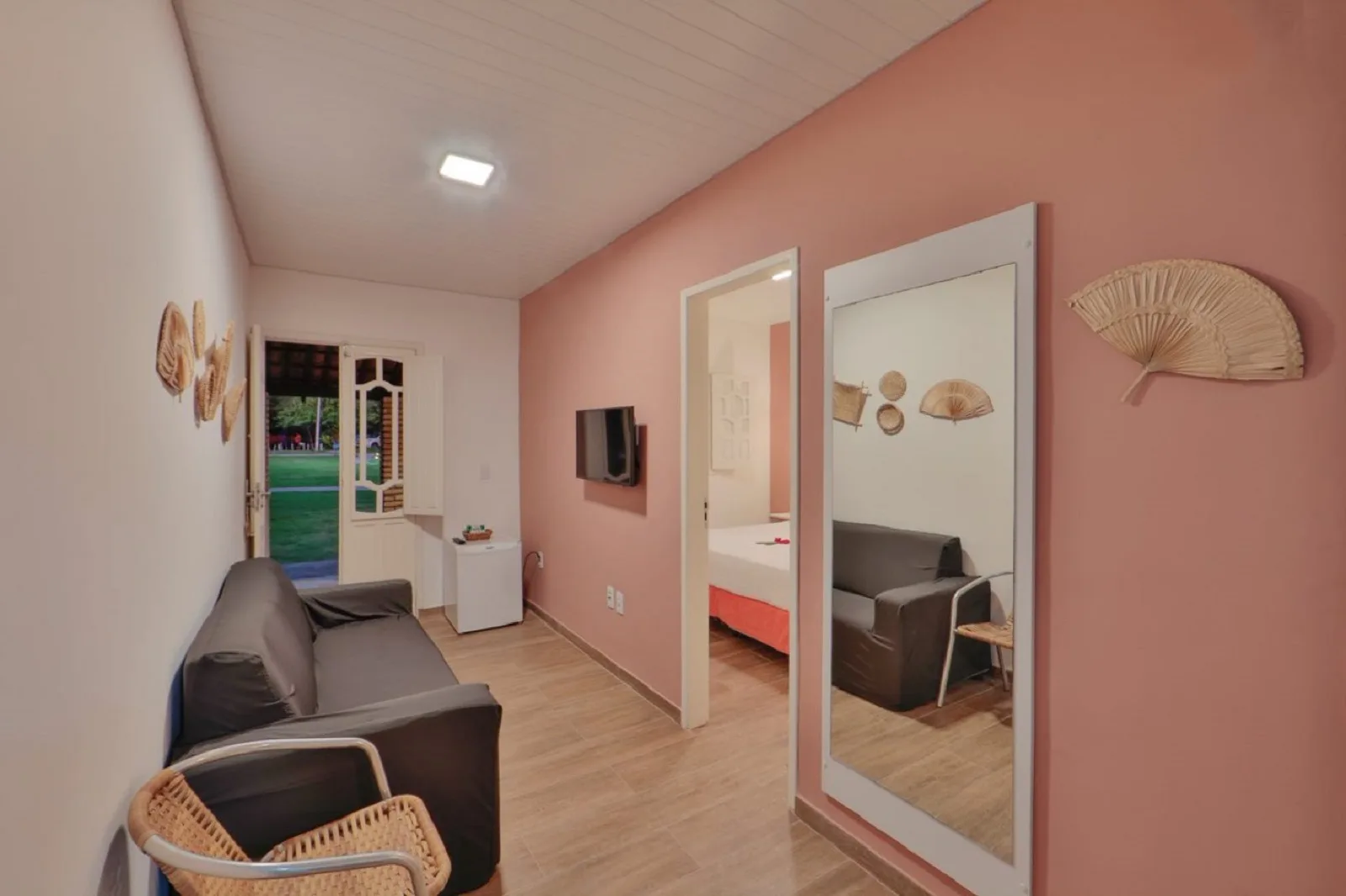 Família Econômico, sala de estar com sofá, espelho e vista para o jardim pela porta
