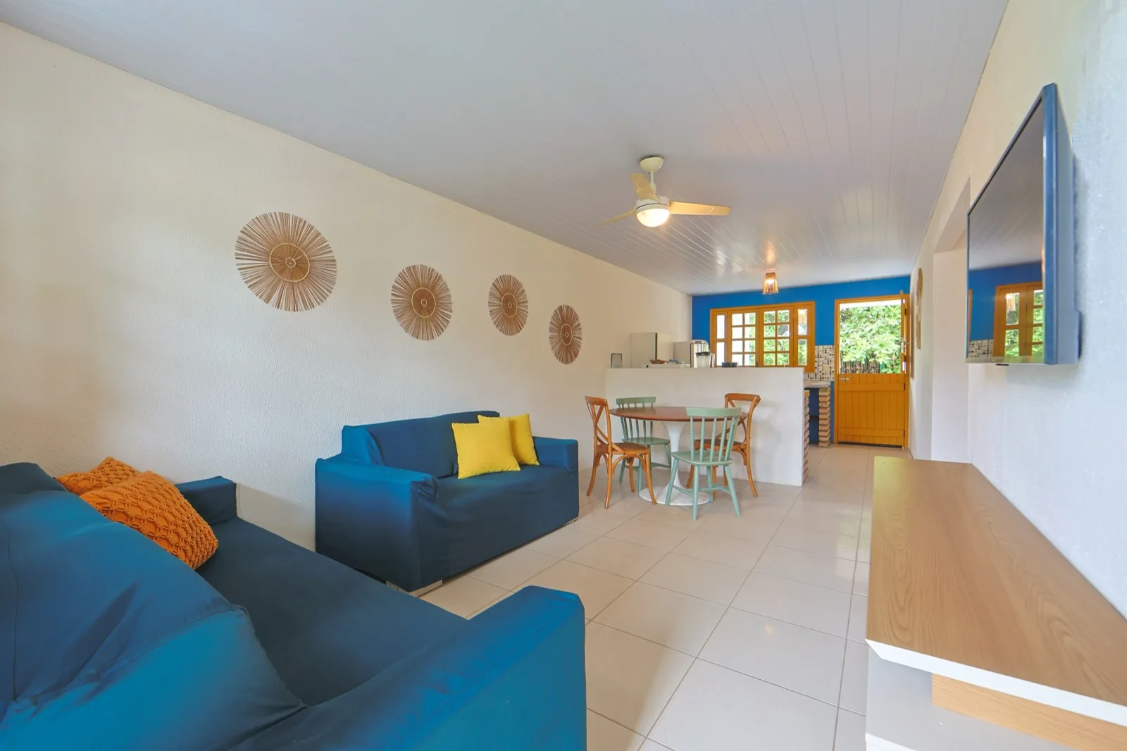 Casa Haras, sala de estar com sofás azuis integrada à cozinha e mesa de jantar
