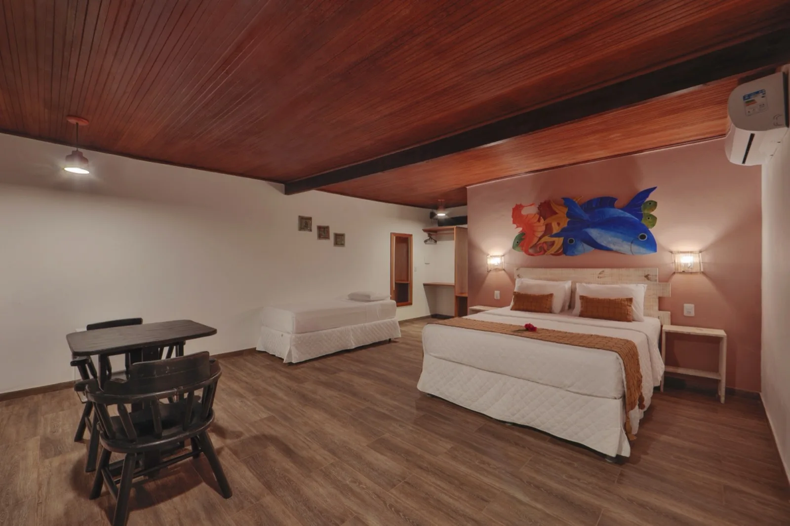 Suíte ampla do Chalé Vista Mar com cama de casal, cama auxiliar, ar-condicionado e painel artístico de peixes