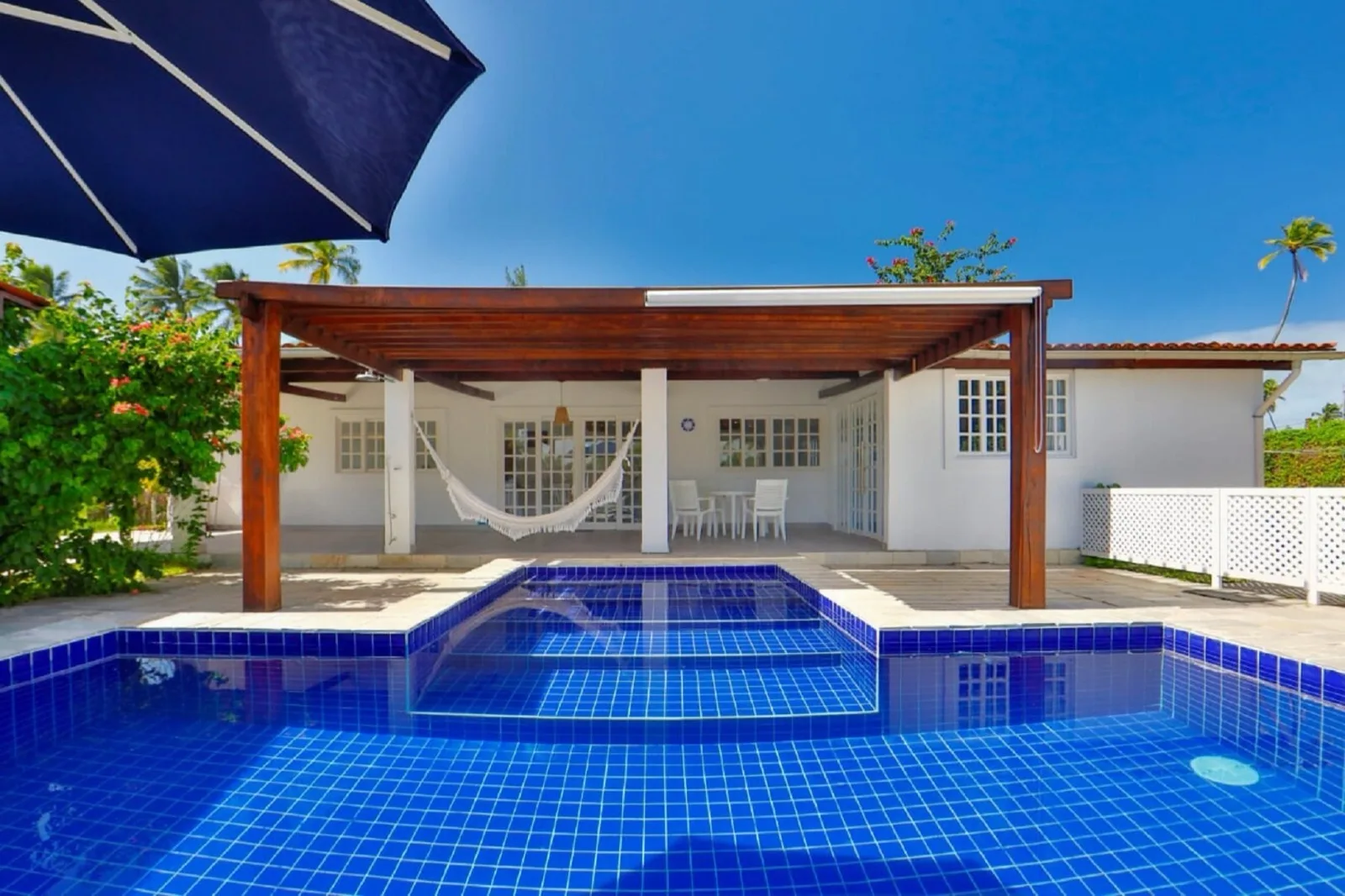 Villa com Piscina Privativa, piscina de borda infinita com deck, pergolado de madeira e varanda com rede