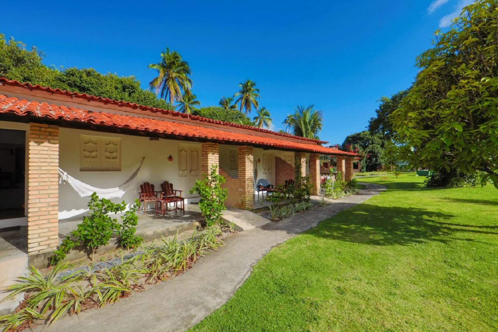 Família Econômico, fachada do bloco com varanda, rede e jardim tropical