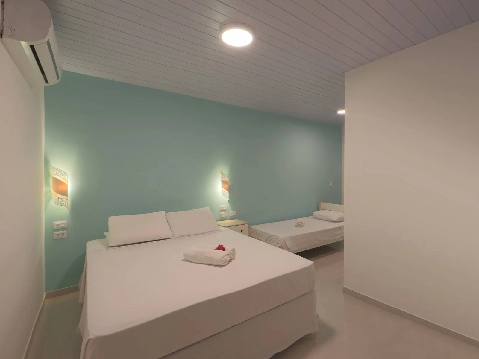 Vista Jardim, quarto triplo com parede verde-água, cama de casal e cama de solteiro