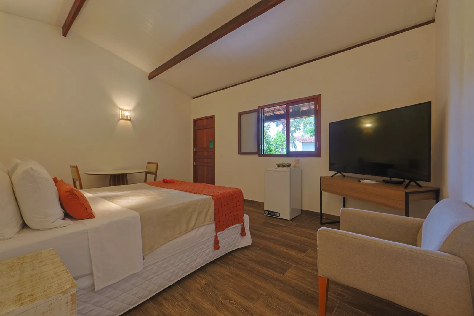 Quarto da Suíte com cama de casal, sofá, TV e mesa de apoio