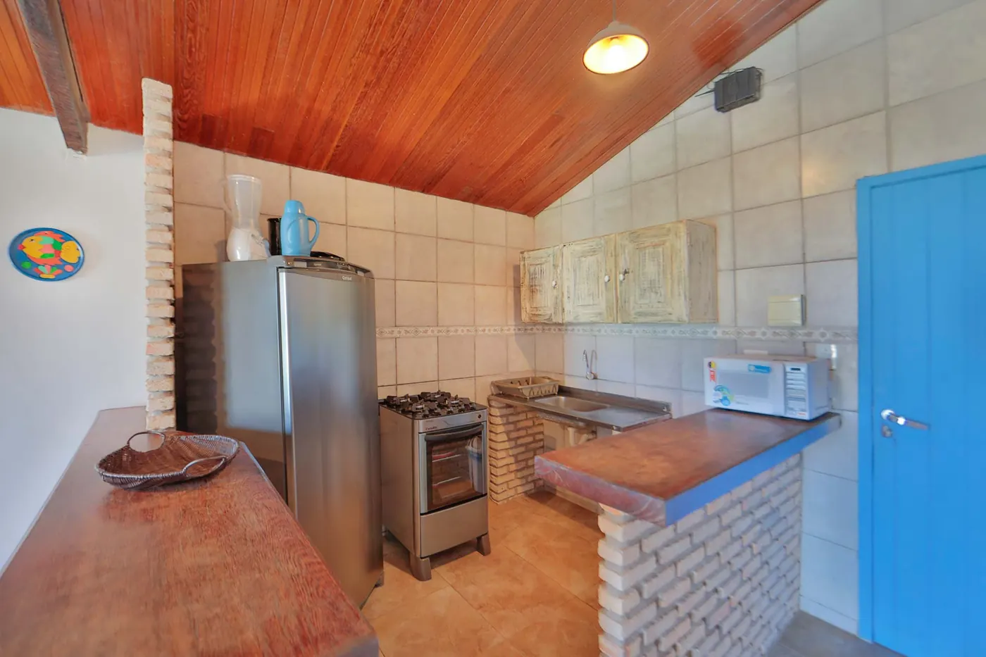 Cozinha equipada com fogão, geladeira, micro-ondas e bancada