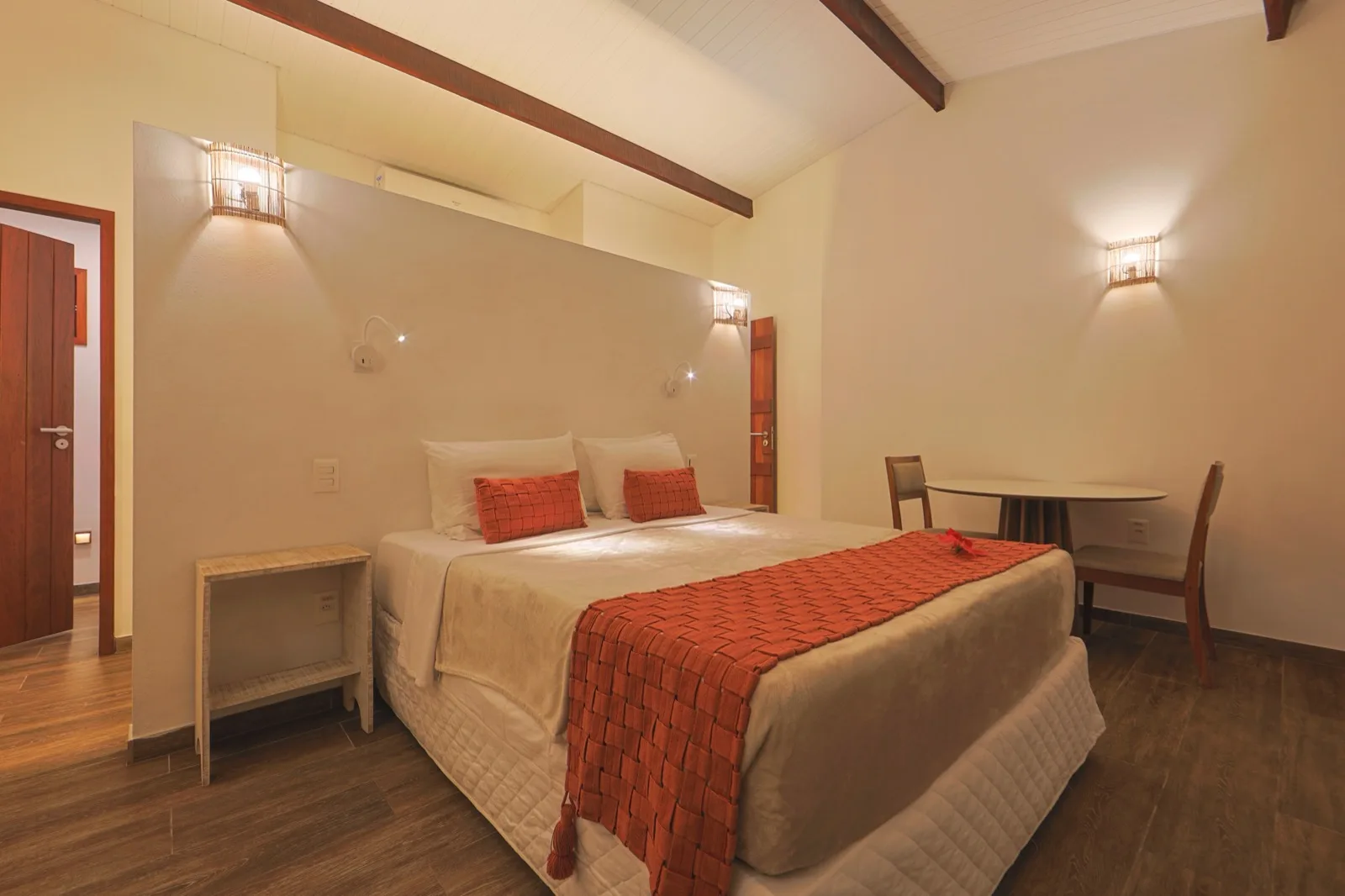 Suíte à noite com cama de casal, mesa de apoio e cadeiras