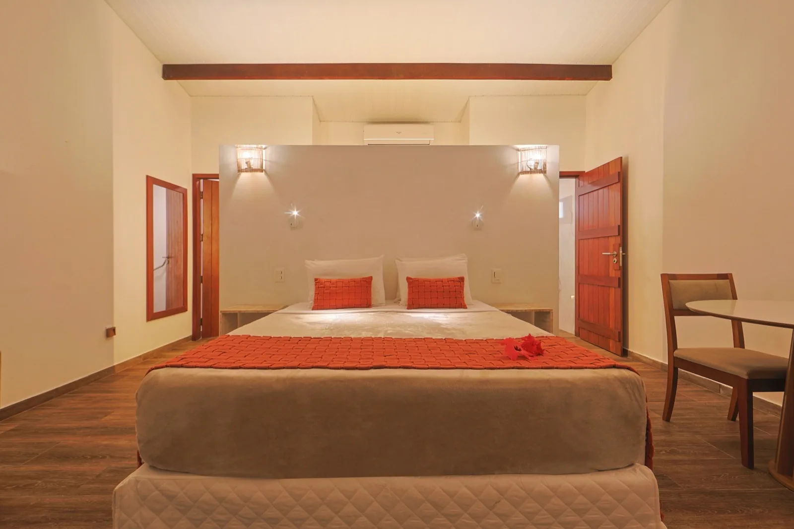 Cama de casal da Suíte com manta terracota e cabeceira em parede clara